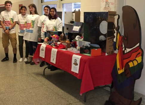 The Mole Day winners pose with their projects displayed. Ayden Cassano, Mya Ramos, Ashley Tolocka, Jake Vasquez, and Shayna Mangal received a glow in the dark T-shirt of a periodic table as their reward. 
