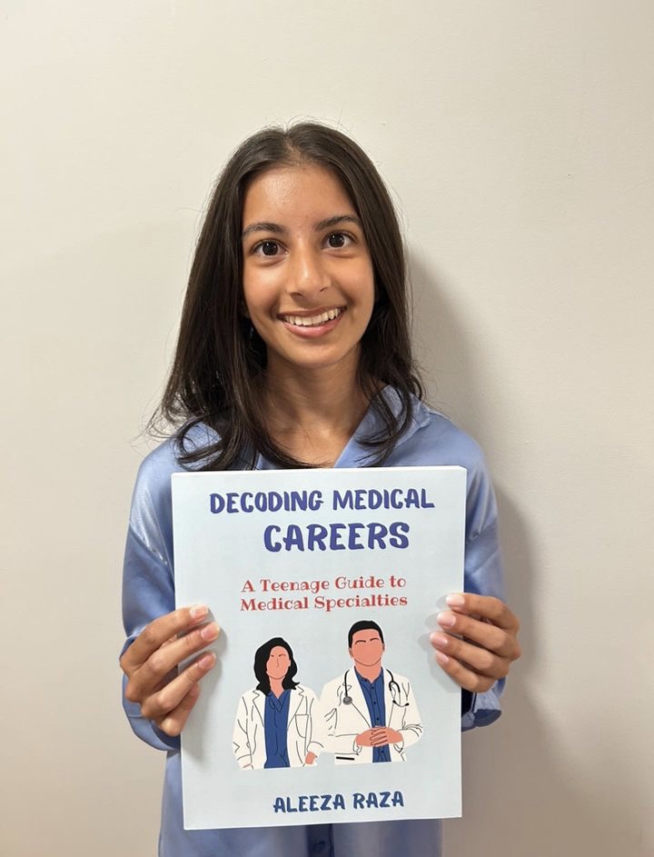 Sophomore Aleeza Raza poses with her book Decoding Medical Careers